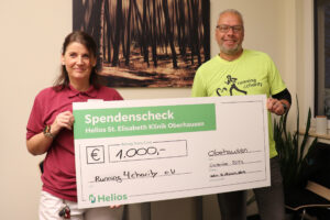 Silke Taubner von der Helios St. Elisabeth Klinik Oberhausen überreicht den Spendenscheck an den Vorsitzenden von running4charity. Diese Helios Oberhausen Spende running4charity würdigt das Engagement des Vereins.